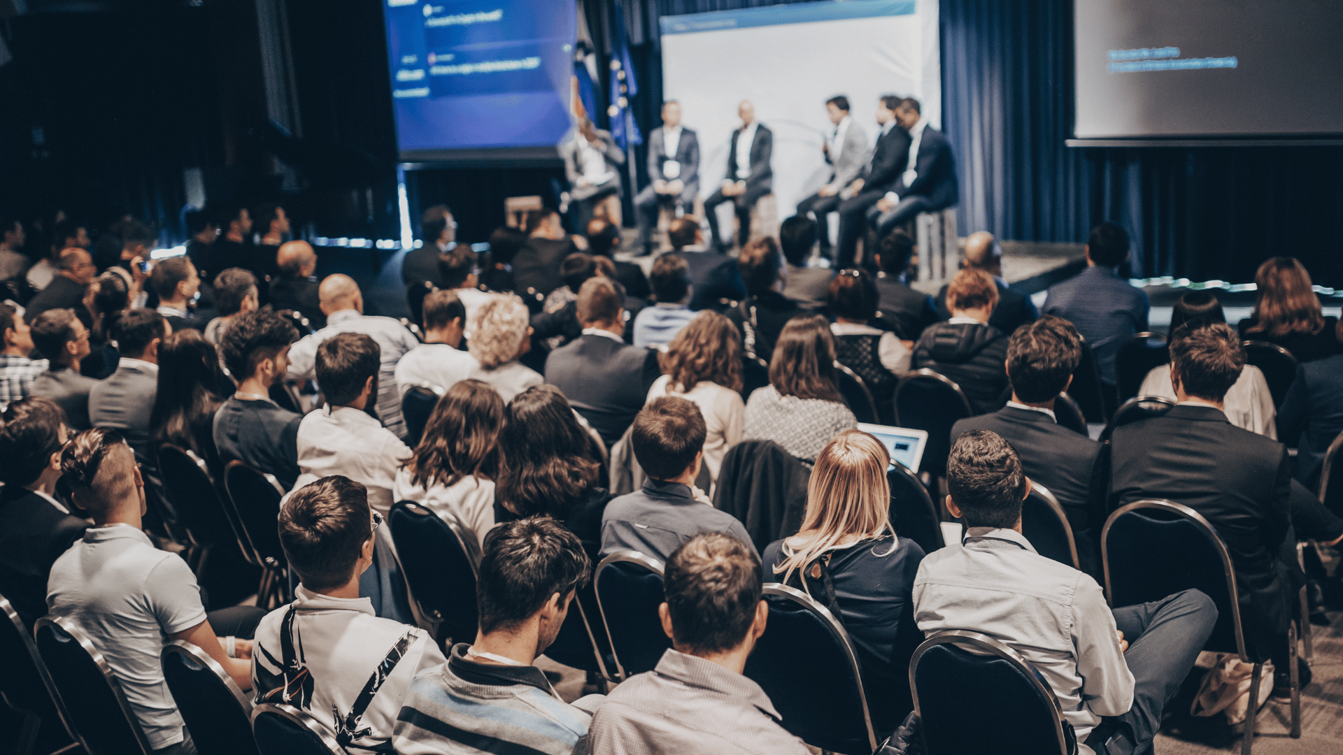 Audience attending a technology conference panel discussion, with speakers on stage engaging in conversation